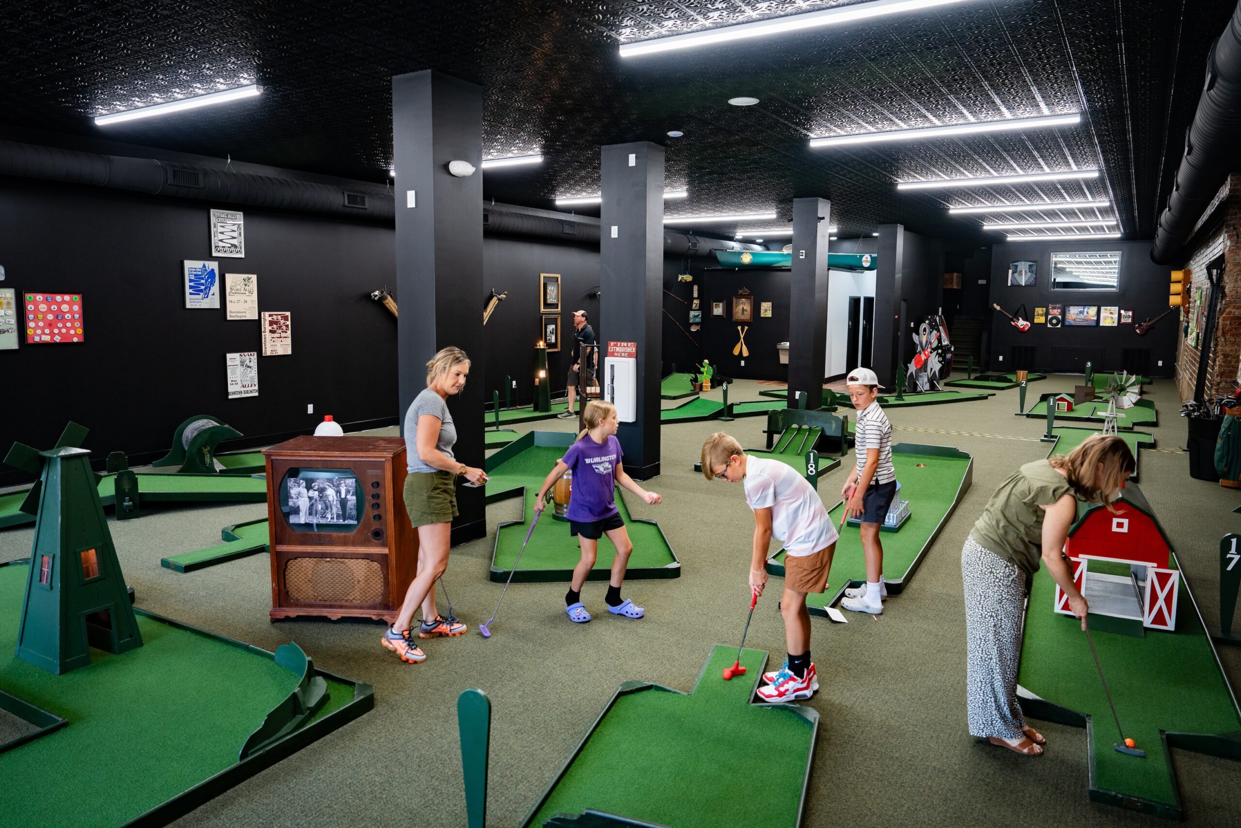 Families playing indoor mini golf